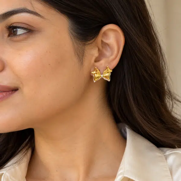 Model wearing chic gold plated bow earrings on her ear