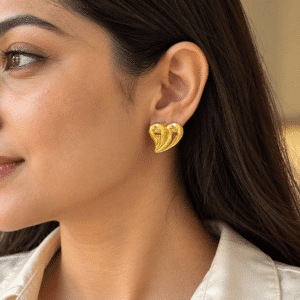 A model wearing elegant gold plated heart earrings with a soft, minimalist aesthetic
