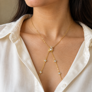 A model wearing the gold-plated Aurelia Pearl Body Necklace over a white shirt