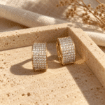 Wide Pavé Gold-Tone Hoop Earrings styled on a display