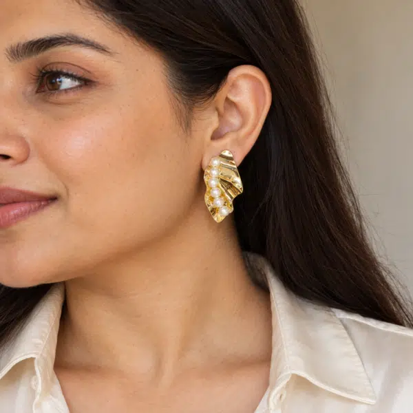 Model wearing elegant gold pearl statement earrings