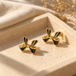 A pair of elegant black enamel bow gold plated earrings on a white background