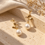 Papillon Pearl Gold Drop Earrings styled on a display