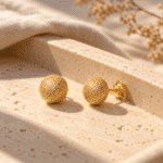 Stardust Sphere Gold Studs styled on a display