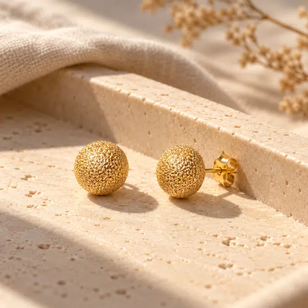 Stardust Sphere Gold Studs styled on a display
